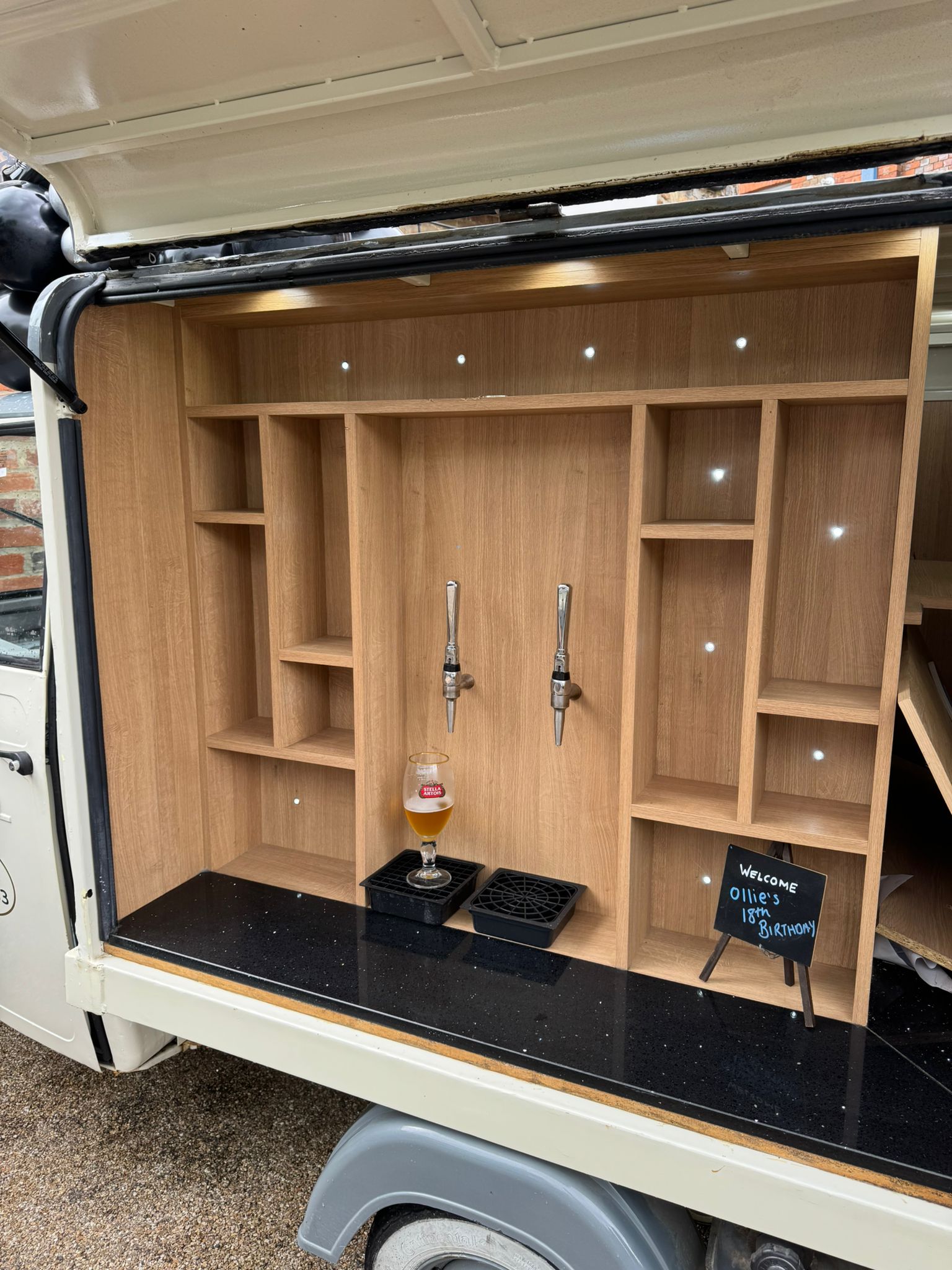 Close-up of the tuktuk bar interior showing oak shelving, two draught beer taps and a poured beer